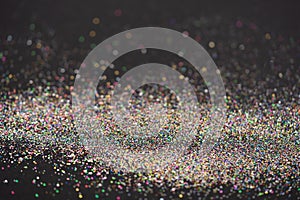 Beautiful Christmas light background. Abstract glitter bokeh and scattered sparkles in gold, on black