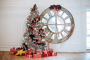 Beautiful Christmas living room with decorated Christmas tree, gifts in front of whate wall. New year tree with red and gold decor