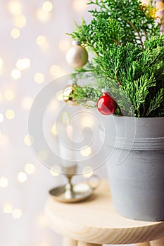 Beautiful Christmas New Year Background. Decorated potted juniper tree decorated with red balls golden garland lights. Lit candle