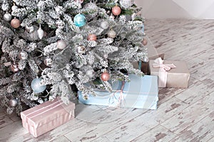 Beautiful Christmas presents  near Christmas tree in living room. New Year. Pink and blue gift boxes with ribbons. Winter Holiday