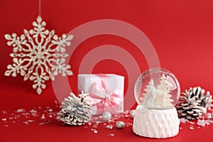 Beautiful Christmas snow globe and festive decor on red background. Space for text