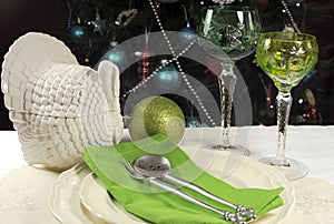 Beautiful Christmas table setting in front of Christmas Tree, with green crystal wine goblet glasses