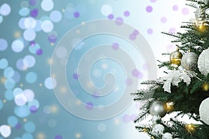 Beautiful Christmas tree with bright baubles against blurred lights on light blue background, closeup. Space for text