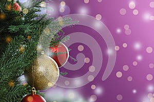 Beautiful Christmas tree with bright baubles against blurred lights on violet background, closeup. Space for text