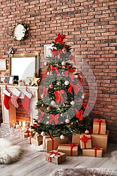 Beautiful Christmas tree and gifts near fireplace with stockings indoors
