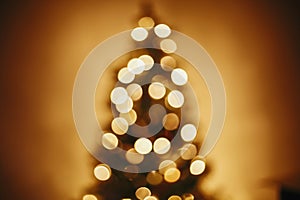 beautiful christmas tree golden lights in festive room. christmas abstract background, blur defocused bokeh of yellow glowing de