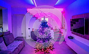 Beautiful Christmas Tree inside a modern house with led strips lighting. Holidays concept