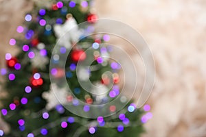 Beautiful Christmas tree with lights against brown background, blurred view