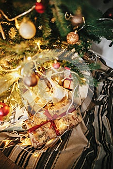 beautiful christmas tree with ornaments, golden lights and presents in festive room. red and gold balls on pine tree branches. de