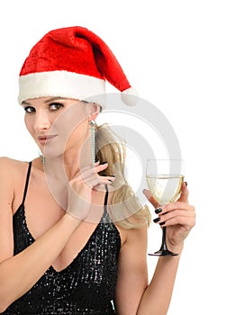 Beautiful Christmas woman in a Santa hat with a glass of champagne in a black tight dress. The concept of Christmas greetings