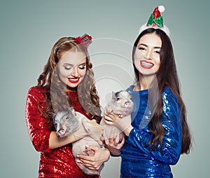 Beautiful Christmas women in glitter dress holding little pigs. Christmas and New Year party concept
