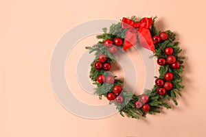 Beautiful Christmas wreath with festive decor on coral wall, space for text