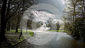 The beautiful city park of the city of Apeldoorn with the large ponds and beautiful fountain on an early spring day