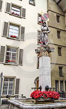 Beautiful City Street View of the colorful medieval Banneret statue on top of elaborate fountain in Bern, Switzerland.