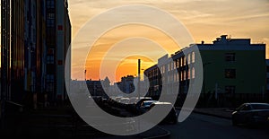 Beautiful city sunset. Evening photo of Parking space in a small town. Reflection of sun in Windows of three-storey building