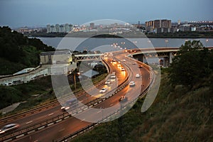 Beautiful cityscape with modern curved road or bridge highway. Stream of cars with headlights