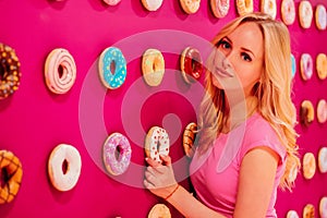 Beautiful clamour blonde girl in pink closeup on the pink donut background
