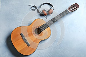 Beautiful classical guitar and headphones on color background