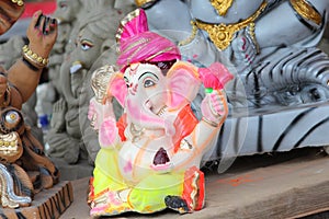 A Beautiful clay statue/Idol of an Indian god Lord Ganesha decorated with colorful drapery and Marigold garland