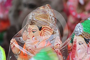 A Beautiful clay statue/Idol of an Indian god Lord Ganesha decorated with colorful drapery and Marigold garland