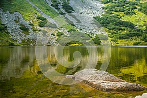 A beautiful, clean lake in the mountain valley in calm, sunny day. Mountain landscape with water in summer.