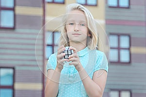 Beautiful and clever blonde kid girl solves a mirror cube puzzle