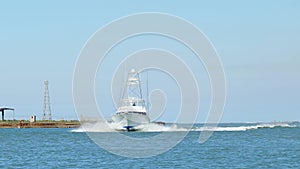 Beautiful clip of white fishing yacht boat on blue water as it turns and slows down to enter the harbor on a sunny day