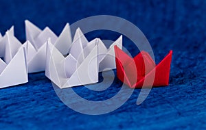 Beautiful close up shot of a red paper boat with white boats on blue paper as ocean