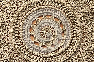 Beautiful closeup beige crochet doily on wooden background