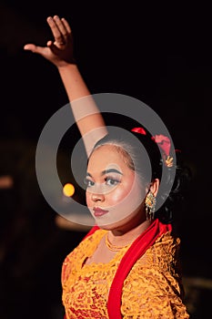 The beautiful closeup face of a Javanese woman with make-up at a traditional dance performance while wearing a yellow costume