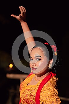 The beautiful closeup face of a Javanese woman with make-up at a traditional dance performance while wearing a yellow costume