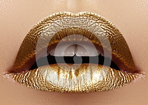 Beautiful closeup with female plump lips with gold color makeup. Fashion celebrate make-up, glitter cosmetic