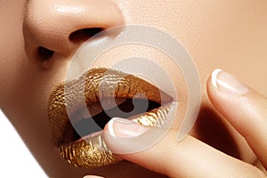 Beautiful closeup with female plump lips with gold color makeup. Fashion celebrate make-up, glitter cosmetic