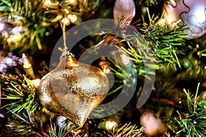 Beautiful closeup of a golden ornament and other decorations on a Christmas tree with lights