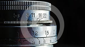 Beautiful closeup of an old vintage camera lens with aperture values on a black background. Photography concept with copy