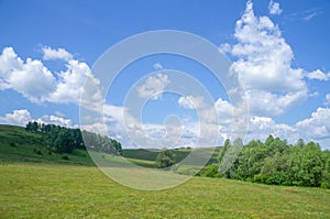 Beautiful clouds in the blue sky bright summer sun illuminates the green meadows on the hills