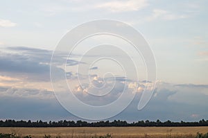 Beautiful clouds over the evening fields. Cloudy day in a picturesque summer valley.