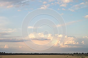 Beautiful clouds over the evening fields. Cloudy day in a picturesque summer valley.