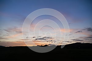 Beautiful clouds over the green meadow during sunrise or sunset.