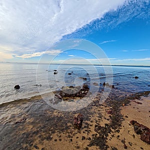 Beautiful cloudscape over a calm waveless sea with a rocky coastline