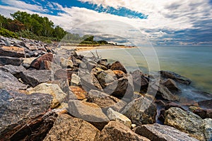 Beautiful cloudy landscape with coast of peninsula with big beach with walking people seen from behind giant rocks photo