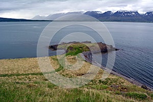 Beautiful coast of the fjord at the forefront of the snowy peaks in the west of Iceland