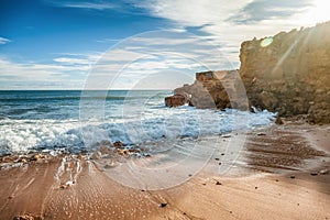 Beautiful coast of the ocean, Algarve, Portugal. Waves break against the rocks in the sun