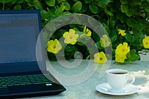 Beautiful coffee mug on the marble table and laptop next to it.