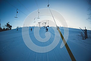 Beautiful cold mountain view of ski resort, sunny winter day with slope, piste and ski lift, with group of mountain downhill