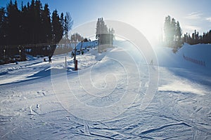 Beautiful cold mountain view of ski resort, sunny winter day with slope, piste and ski lift, with group of mountain downhill