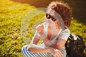 Beautiful college girl chilling sitting on lawn in campus park