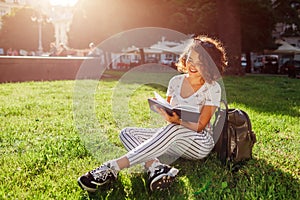 Beautiful college girl reading a book in campus park. Happy woman student learning outdoors