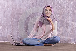 Beautiful college student wearing hijab sitiing on the floor aft