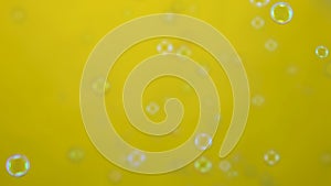 Beautiful colored soap bubbles fly indoors on a yellow background. Round bubbles flying in the air and sparkling with